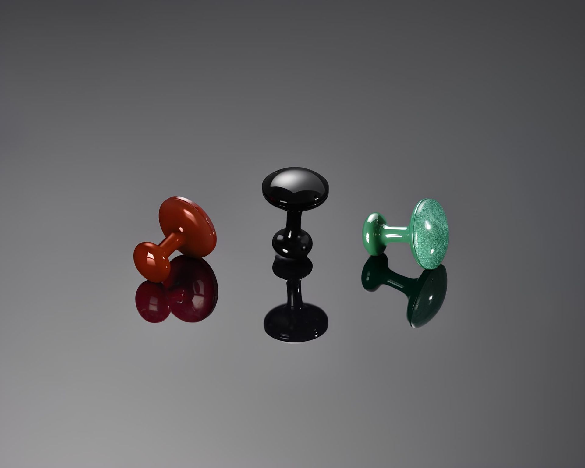 Three shiny cufflinks in the colors red, black and green, placed next to each other on a black surface.